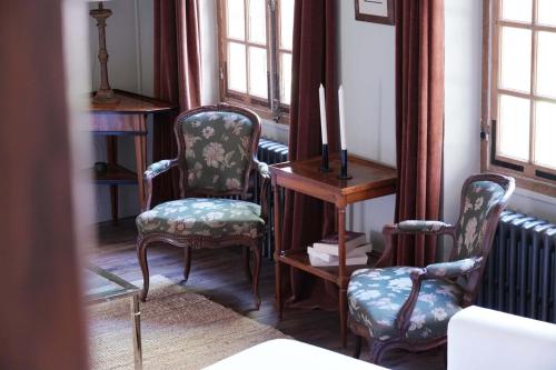 Una habitación con dos sillas y una mesa y ventanas. en Maison de Sylvain, en Barjouville
