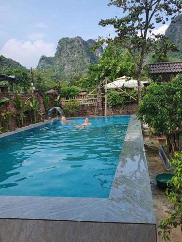 zwei Personen in einem Schwimmbad mit Bergen im Hintergrund in der Unterkunft Mellowmoo Homestay in Nguyễn Thôn