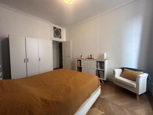 a bedroom with a bed and a chair at Herem Charme de l ancien en centre ville in Clermont-Ferrand