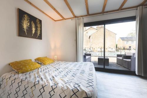 a bedroom with a bed and a large window at Le gite du marronnier in Montamisé
