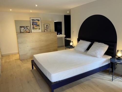 a bedroom with a large bed with a black headboard at Le troglo du château in Beaumont