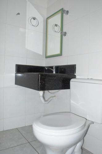 a bathroom with a white toilet and a mirror at Brisa Do Vale Pousada in Itaobim