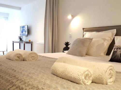 un dormitorio con una cama con sábanas y almohadas blancas en Luxury studio near beaches and shops, en Perros-Guirec
