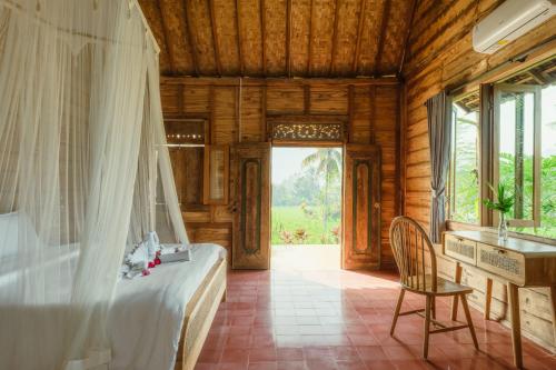 a bedroom with a bed and a desk and a window at Green vanilla kabin in Silebeng