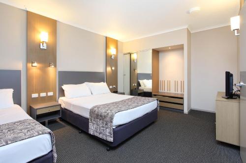 a hotel room with two beds and a flat screen tv at Brisbane International Virginia in Brisbane