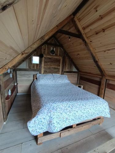 a bed in a room with a wooden ceiling at Cabaña Bambú - Roca Glamping Suesca in Santa Isabel