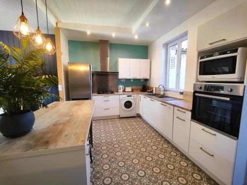 a large kitchen with white cabinets and a dishwasher at Villa Garona avec billard proche Pyrénées in Cazères