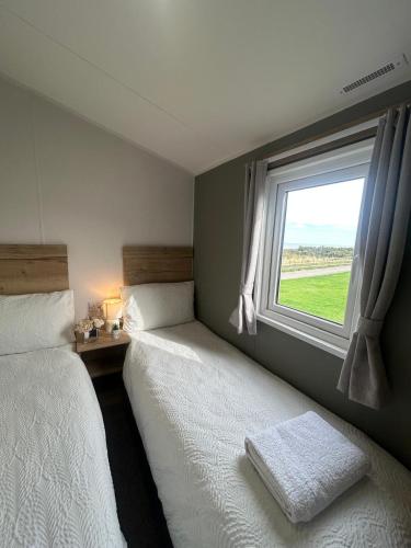 two beds in a bedroom with a window at Sea View by the beach at Crimdon Dene Holiday Park in Hartlepool