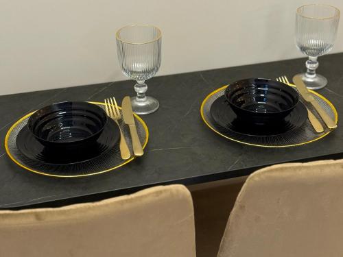 ein Tisch mit zwei schwarzen Tellern und zwei Weingläsern in der Unterkunft Golden Eden Wieniawska - Rezydencja Ogród Saski in Lublin
