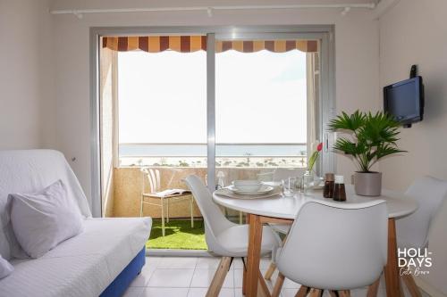 a living room with a table and chairs and a view of the ocean at Holidays Rincón Vista Mar PL4 in Empuriabrava