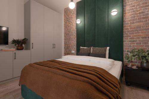 a bedroom with a large bed with a brick wall at Harbor Apartments - Aparthotel przy Rynku in Katowice