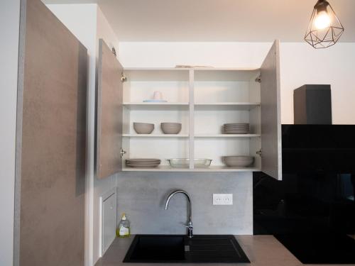 a kitchen with a sink and a shelf with dishes at Djoka ParisNord CDG StadedeFrance in Le Blanc-Mesnil