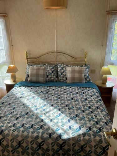 a bedroom with a large bed with a blue and white comforter at i7 Millfields 6 Berth Luxury Caravan DG & GCH Familys Only And Lead Person Must Be Over 30 in Ingoldmells