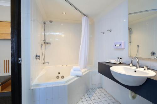 une salle de bain avec une baignoire et un lavabo et une baignoire dans l'établissement Brisbane International Virginia, à Brisbane