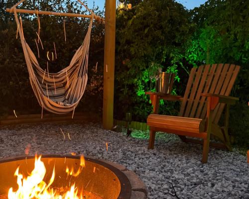 a hammock and a bench next to a fire pit at Stylish 2 Bedroom Cottage with Hot Tub and Parking in Bewdley