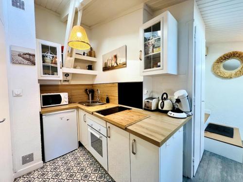 a small kitchen with white cabinets and a sink at Le Petit Réaumur - Coeur de ville in La Rochelle