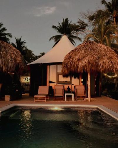 a resort with a swimming pool with chairs and a tent at Almare Zonte - BeachFront Glamping Hotel in El Zonte