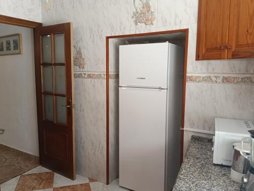 una nevera blanca en una cocina junto a una puerta en Casa Algarabía, en Sanlúcar de Barrameda
