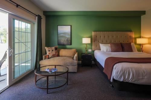 a bedroom with a bed and a couch and a chair at On the River Inn in Woodstock