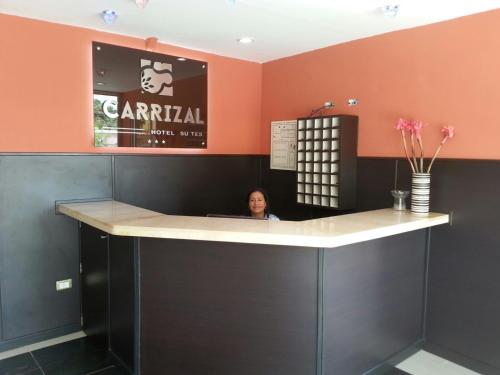a woman sitting at a bar in a restaurant at Hotel Carrizal Suites in Barinas