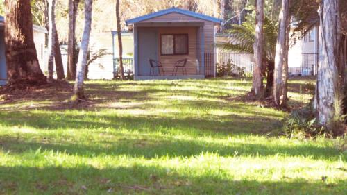 a small house in a yard with trees at Strahan Retreat Holiday Park in Strahan