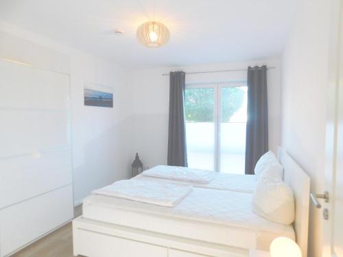 a white bedroom with a bed and a window at FeWo "Hafenquartier" in Barth