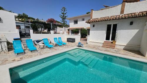 a swimming pool with blue chairs and a house at El Camerote in Mijas