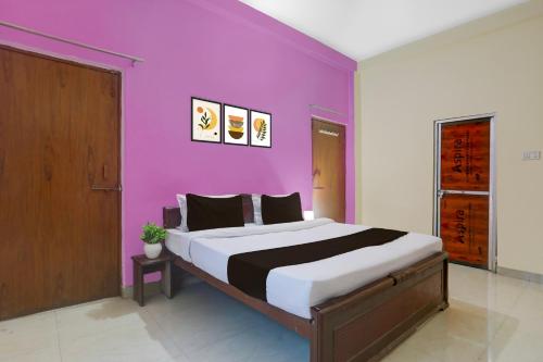 a bedroom with a large bed with a purple wall at Hotel O BABA GUEST HOUSE in Shivāpur