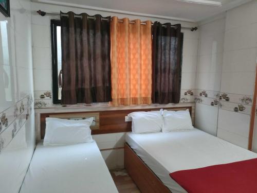 two beds in a small room with a window at Hotel O Sai Laxmi in Shirdi