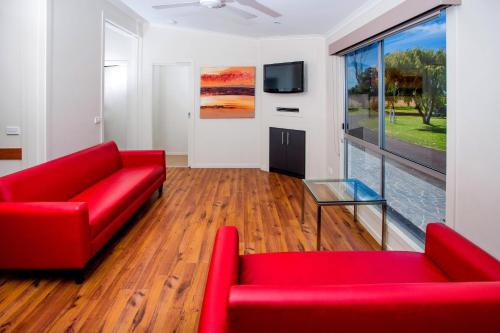 a living room with two red couches and a tv at BIG4 Port Fairy Holiday Park in Port Fairy