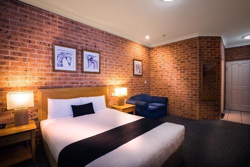 a bedroom with a large bed and a brick wall at Akuna Motor Inn and Apartments in Dubbo