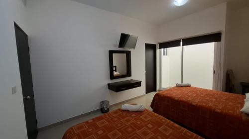 ein Hotelzimmer mit zwei Betten und einem Fernseher in der Unterkunft LAS OLAS in Paraíso