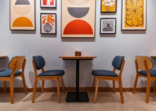 um quarto com quatro cadeiras e pinturas na parede em Anise Luxe Home em Cidade de Ho Chi Minh