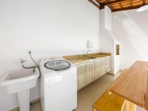 een wasmachine in een keuken met een wastafel bij Curta Praia de Armação - Casa Violeta in Penha