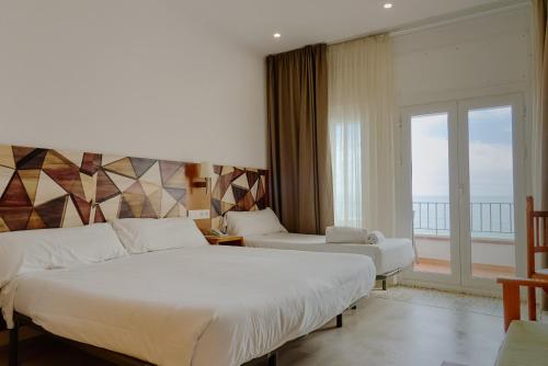a hotel room with two beds and a balcony at Hotel Miramar Badalona in Badalona