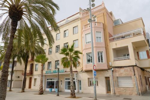 a building with palm trees in front of it at Hotel Miramar Badalona in Badalona
