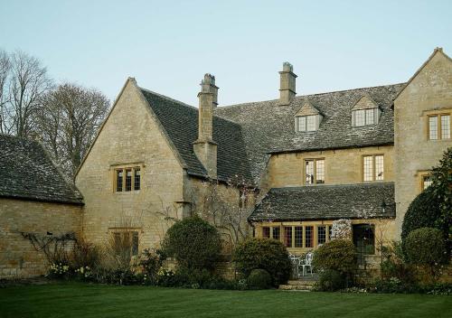 una vieja casa de piedra con césped delante en Pye Corner a Cotswold Manor with outdoor heated pool, en Broadway