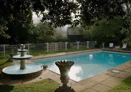 una piscina con una fuente en un patio en Pye Corner a Cotswold Manor with outdoor heated pool, en Broadway