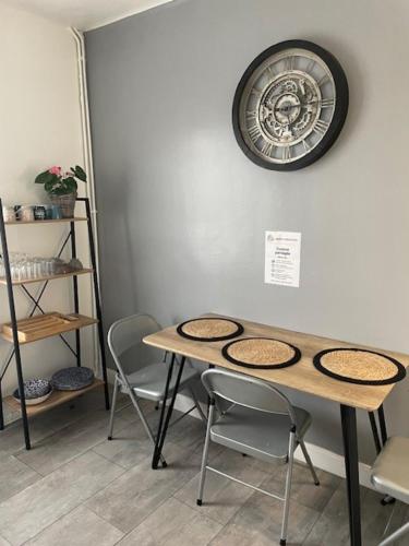 a table with chairs and a clock on the wall at Le Logis Saumur in Saumur