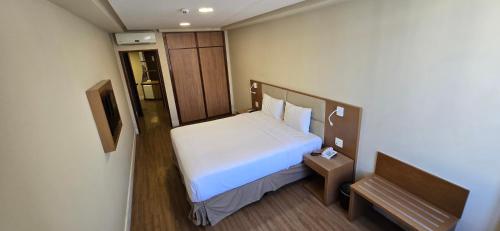 a small bedroom with a white bed and a bench at Mirador Rio Copacabana Hotel in Rio de Janeiro