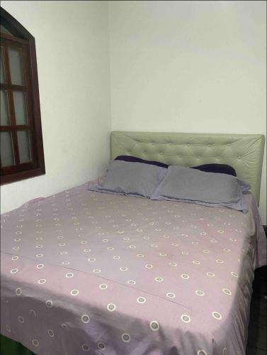 a bedroom with a bed with a purple bedspread at Sítio Serra Verde in Guapimirim