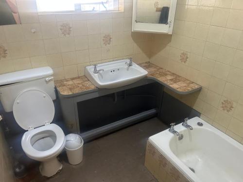 Un baño con inodoro, lavabo y bañera. en The Cargo Club Guesthouse, en Ventersburg