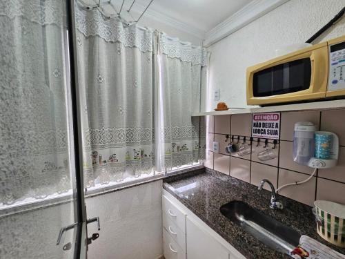 Una pequeña cocina con fregadero y microondas. en Flat Di Roma Aconchego1 em Rio Quente Go - Hot Park, en Rio Quente