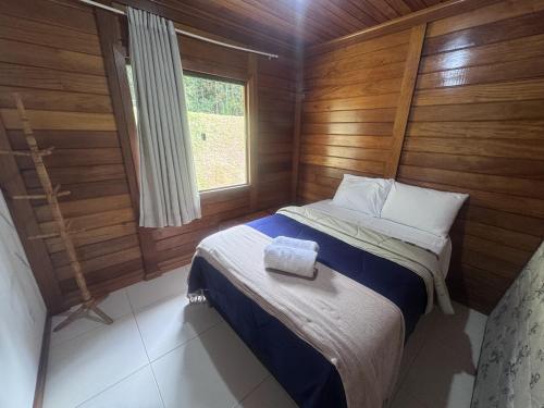 a small bed in a wooden room with a window at Sítio Martinelli, Caravaggio in Santa Teresa