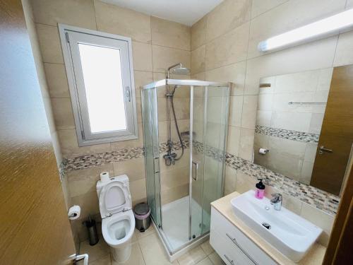 a bathroom with a shower and a toilet and a sink at Rose Gardens Cozy Villa in Paphos City