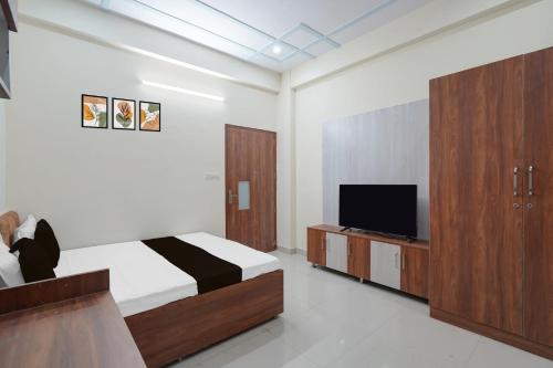 a bedroom with a bed and a flat screen tv at Hotel O Radha Residency in Dahmi