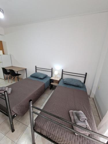 2 Einzelbetten in einem Zimmer mit einem Tisch und einem Tisch in der Unterkunft Diana's Cozy 24 Studio in Ioannina