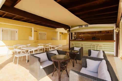 un patio avec tables et chaises et un bar dans l'établissement Solena Studios Kavos, à Kavos