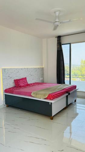 a bed in a room with a large window at Air Rooms in Lohārakot