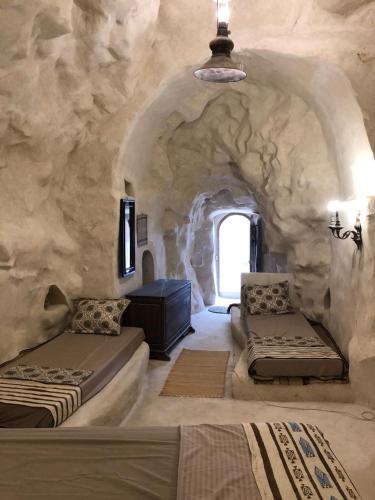 a room with two beds and a stone wall at échappée troglodyte unique in Tūjān